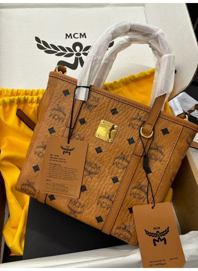 حقيبة توت صغيرة مصنوعة من جلد طبيعي ذو جودة عالية، تحمل علامة MCM، بتصميم تقليدي مزخرف.